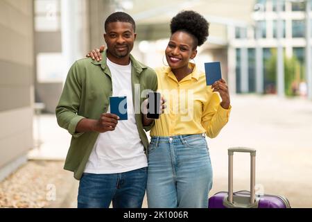 Afrikanische Touristen Paar Zeigt Smartphone-Bildschirm Holding Pässe Am Flughafen Stockfoto