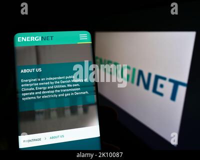 Person mit Smartphone und Website des dänischen Übertragungsnetzbetreibers Energinet auf dem Bildschirm mit Logo. Konzentrieren Sie sich auf die Mitte des Telefondisplays. Stockfoto