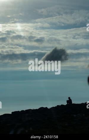 Frau Silhouetted saß auf einem Hügel am Pass des Viehs, applecross, schottland, großbritannien Stockfoto