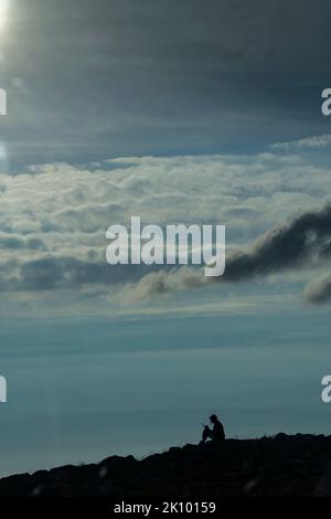 Frau Silhouetted saß auf einem Hügel am Pass des Viehs, applecross, schottland, großbritannien Stockfoto