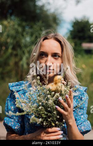 Schönes Mädchen mit Wildblumen und Entchen in ihren Händen Stockfoto