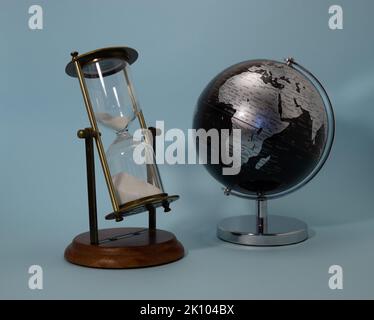 Retro Sanduhr Komposition mit schwarzem Globus auf himmlischem Hintergrund Stockfoto