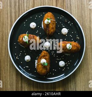 Hausgemachte traditionelle spanische Kroketten auf einem schwarzen Teller. Draufsicht. Stockfoto