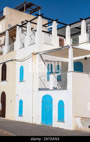 Altes Stadtgebäude mit leuchtend blauen Türen und Fensterläden entlang der Stadtmauer in Alghero, Sardinien, Italien Stockfoto