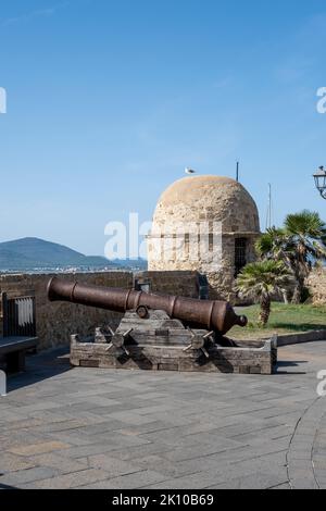 Alte Kanonen auf den Wällen der Altstadt von Alghero, Sardinien, Italien, mit Blick auf die Klippen und das Vorgebirge von Capo Caccia Stockfoto