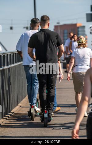 Fußgänger und E-Scooter auf einem Bürgersteig, sich gegenseitig in die Nähe kommen, illegales Fahren auf dem Bürgersteig durch E-Scooter-Nutzer, Düsseldorf, NRW, Stockfoto