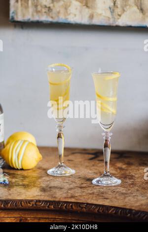 Zwei Sektflöten mit einem französischen 75-Cocktail und langen Zitronenverdrehungen Stockfoto