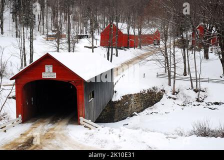 Eine Landstraße fährt durch die rote Green River Covered Bridge in einer schneebedeckten Winterlandschaft in Guilford, Vermont, Neuengland Stockfoto