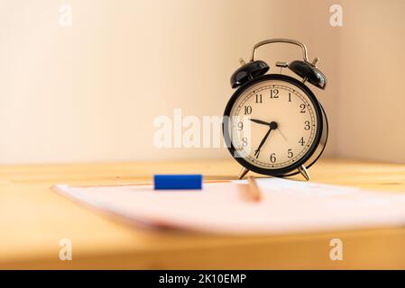 Prüfung im Bildungskonzept, Bleistift, Radiergummi und Wecker auf Holztisch, Stockfoto