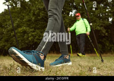 Beschnittenes Bild von Frau und Mann, die mit skandinavischen Stöcken im Herbstwald im Freien spazieren. Nordic Walking, gesunder Lebensstil Stockfoto