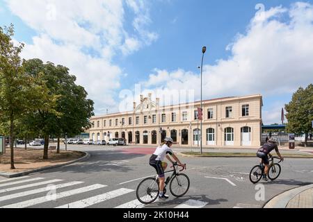 VIC, Spanien - 11. September 2022: Ein Mann und eine Frau auf Fahrrädern, die durch den Verkehrskreis vor dem Vic-S-Bahnhof in Catal fahren Stockfoto