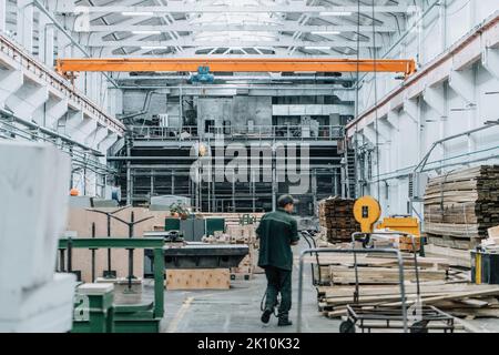 Im Inneren der riesigen Werkshalle mit Holzstapeln. Stockfoto