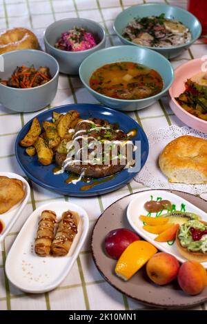 Hausgemachte Würstchen mit Kartoffeln auf dem Esstisch mit verschiedenen Gerichten Stockfoto