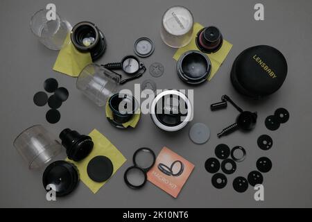 Flatlay von Lensbaby Set auf grauem Hintergrund mit professioneller Beleuchtung. Es gibt vier Objektive mit schwarzen Blendenscheiben und Formen sowie ein Makro-Kit. Stockfoto