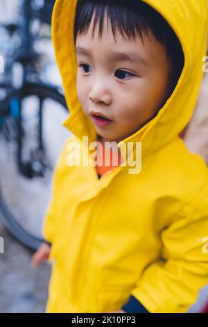Ein kleiner Junge, der einen gelben Regenmantel trägt Stockfoto