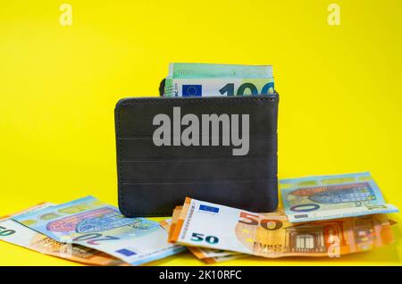 Etui aus echtem Leder mit Euro-Banknoten innen isoliert auf gelbem Hintergrund. Stockfoto