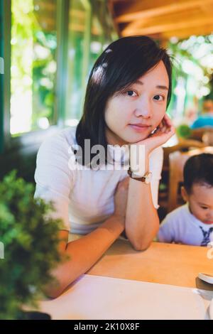 Eine Frau, die in einem Restaurant sitzt. Ihr Kind sitzt neben ihr. Stockfoto