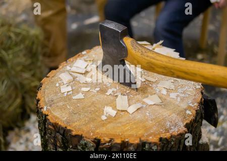 Alte Axt mit Holzgriff in Holzstumpf mit Holzhacken geklebt Stockfoto