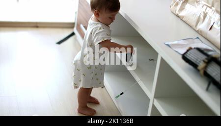 Baby steht auf Möbeln zu Hause Wohnzimmer lehnt. Kleinkind berühren Objekt, Kleinkind Junge mit der Hand greifen Stockfoto