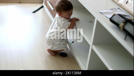 Baby steht auf Möbeln zu Hause Wohnzimmer lehnt. Kleinkind berühren Objekt, Kleinkind Junge mit der Hand greifen Stockfoto