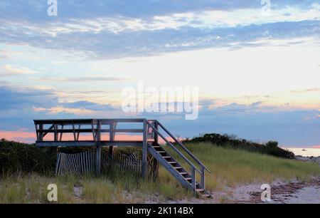 Wunderschöne Cape Cod Strandszene mit farbenfrohem Sommerhimmel und Offshore-Fischerboot. Sanfte Dämmerungsfarben am Corporation Beach in Dennis Mass. Stockfoto