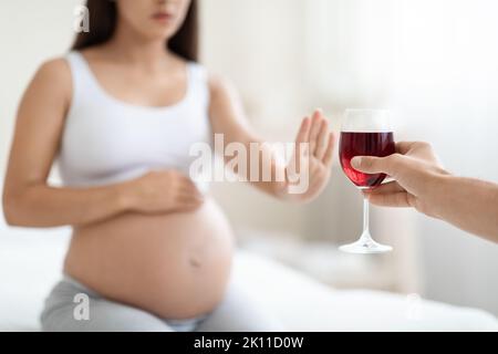 Ein kleiner Junge einer Schwangeren weigert sich, Wein zu trinken Stockfoto