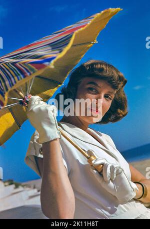 Junge Erwachsene Frau in weißem Kleid mit Sonnenschirm, Kollektion Toni Frisell Stockfoto