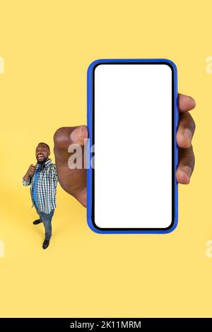 Aufgeregt Schwarz Kerl Zeigt Riesigen Smartphone-Bildschirm Über Gelben Hintergrund Stockfoto