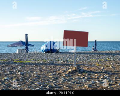 Batumi, Georgia. 09.09.2022 Blankschild am Strand. Mocap. Platz für eine Inschrift an der Küste. Ende der Saison. Bei Sonnenuntergang. Strandurlaub Stockfoto