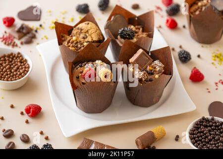 Schokolade Cupcake mit Himbeeren und Waffeln, Schokolade Dekor auf einem beigen Hintergrund.Schokolade Dessert.Schokolade Cupcake.appetitlich Muffin Set Stockfoto