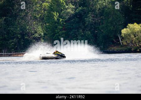 Lake Nokomis, Tomahawk, Wisconsin, USA, August, 20, 2022 - Mann auf einem Jetski, der horizontal über den See fliegt Stockfoto