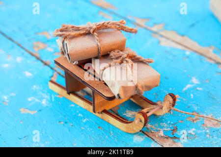 Geschenkschachteln. In Nahaufnahme verpackte Vintage Geschenkbox aus Holz, die auf blauem, altem Holzhintergrund liegt. Geschenk-Box in Bastelpapier. Urlaubskonzept Stockfoto