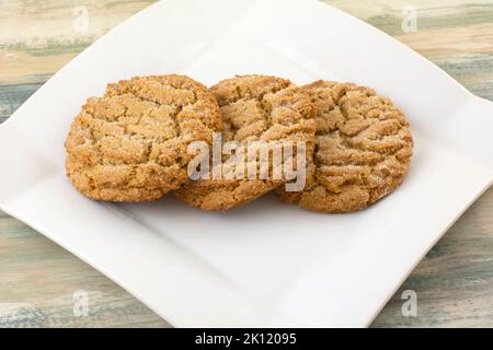Drei gebackene, kauen Ingwerkekse auf weißem Snackteller Stockfoto