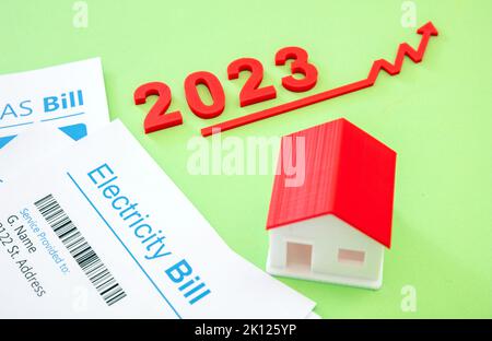 Heizenergie und Wasserkosten steigen im Jahr 2023. Hausmodell, Rechnungen und roter Pfeil nach oben. Stockfoto