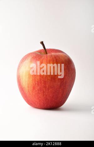 Detail von ganzen reifen roten Apfel isoliert auf weißem Tisch. Vertikale Zusammensetzung. Stockfoto