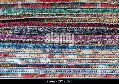 Mehrfarbige Teppich oder Teppich übereinander stapeln. Bunte Textur Hintergrund Stockfoto