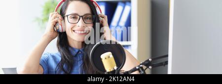 Schöne Frau in Kopfhörern vor dem Mikrofon im Studio Stockfoto