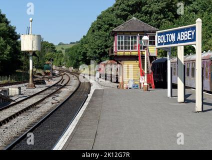 Sehen Sie sich die Linie vom Bahnsteig an der Station Bolton Abbey auf der Embsay & Bolton Abbey Heritage Railway mit Signalbox und Wasserbehälter an. Stockfoto