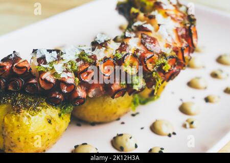 Leckere gegrillte galicische Krake Bein mit gerösteten Kartoffeln und Knoblauch Aioli auf Holztisch Stockfoto