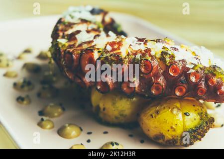 Leckere gegrillte galicische Krake Bein mit gerösteten Kartoffeln und Knoblauch Aioli auf Holztisch Stockfoto