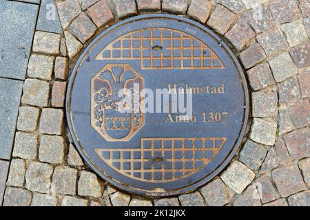 Halmstad, Schweden - 21. August 2022: Halmstad City Kanalabdeckung auf der Straße mit Pflastersteinpflaster, Draufsicht Stockfoto