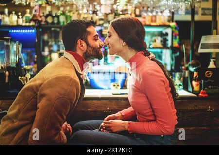 Ein romantisches Paar junger Menschen, die an der Kneipenecke sitzen und sich gegenseitig die Nase reiben - Lifestyle-Konzept für Liebe und Menschen Stockfoto