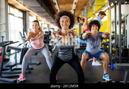 Multiethnische Gruppe von Menschen, die in einem Fitnessstudio trainieren. Trainer und sportlich fit trainierende Personen Stockfoto