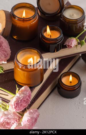 Ein Set verschiedener Duftkerzen in braunen Glasgefäßen. Handgemachte Duftkerze. Sojalkerzen brennen in einem Glas. Aromatherapie und entspannen Sie sich im Spa und zu Hause. Feuer in braunem Glas. Stockfoto