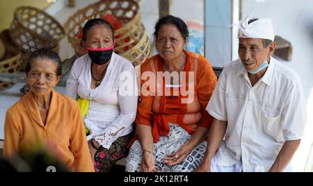 Vier ältere balinesische Frauen und ein Mann in traditioneller Kleidung sitzen zusammen. Bali Menschen häusliches Leben. Stockfoto