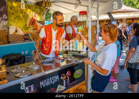 Manavgat, Türkei - 8. September 2022: Mann in türkischer Tracht verkauft traditionelles türkisches Eis in einer Straße von Manavgat, Türkei Stockfoto