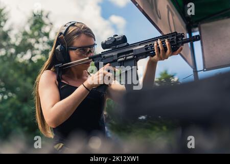 Kaukasische Frau, die auf Schießstand zielt, mittlere Schüsse. Hochwertige Fotos Stockfoto