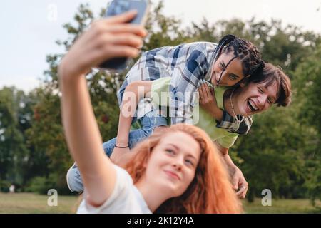 Junge Hipster-Freunde machen lustige Selfie mit dem Smartphone in einem Park draußen auf der Bank. Fotografen und Blogger, die fotografieren, Filmen und Live-Streaming Stockfoto