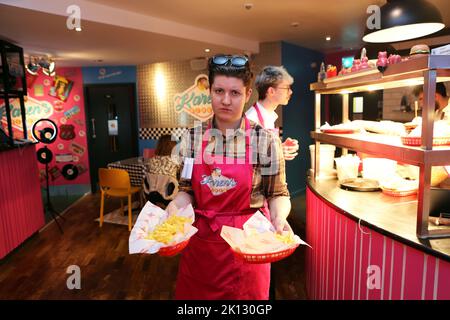 Ein miserabler Mitarbeiter, der Essen an einen Tisch im Karen’s Diner in Prestwich, Manchester, bringt. Karens ist nichts für schwache Nerven, aber es ist perfekt Stockfoto