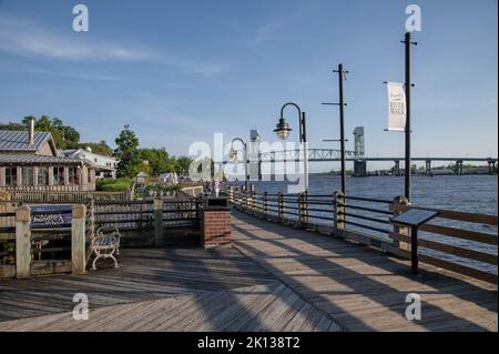 Sonnenuntergang am Riverwalk entlang des Cape Fear River mit Flussbrücke im Hintergrund, Wilmington, North Carolina, USA Stockfoto